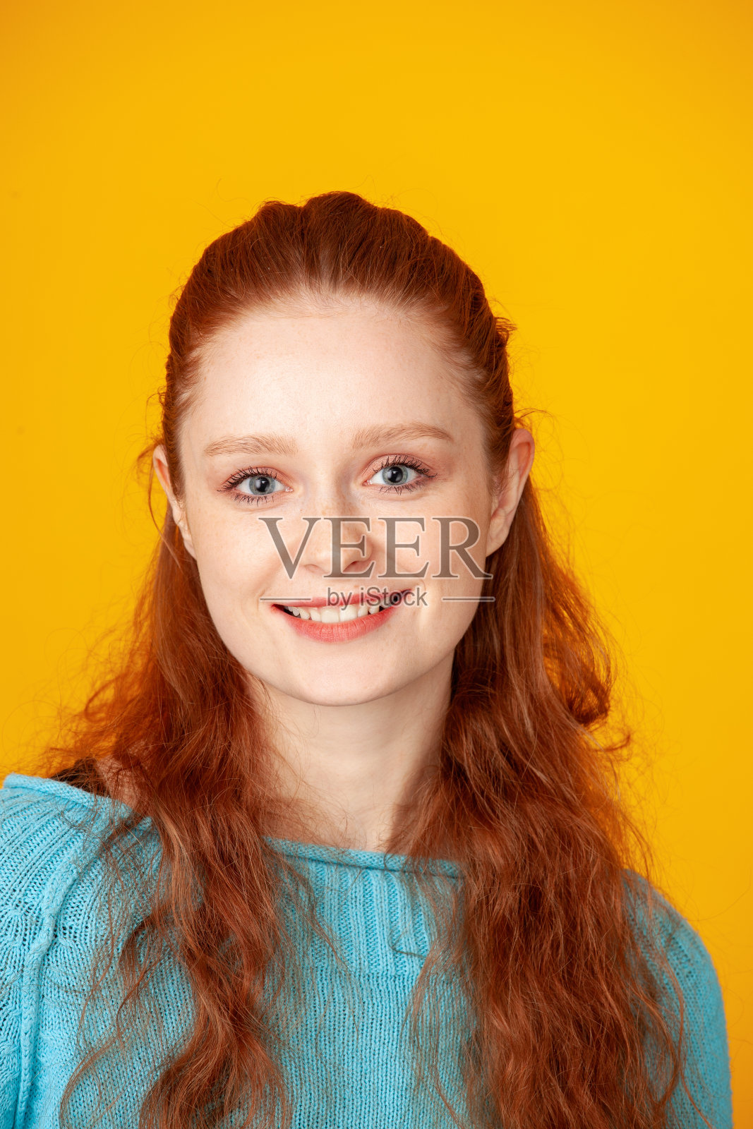 一个年轻迷人、开朗的红发女人在黄色背景下的工作室特写肖像照片摄影图片