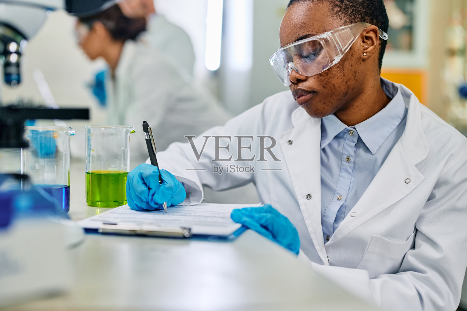 黑人实验室技术员在做科学研究时做笔记。照片摄影图片