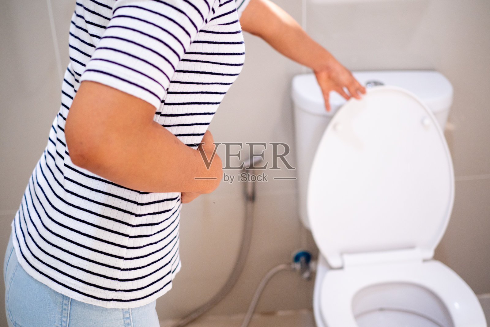 这个女孩胃不舒服，腹泻，站在浴室里。照片摄影图片