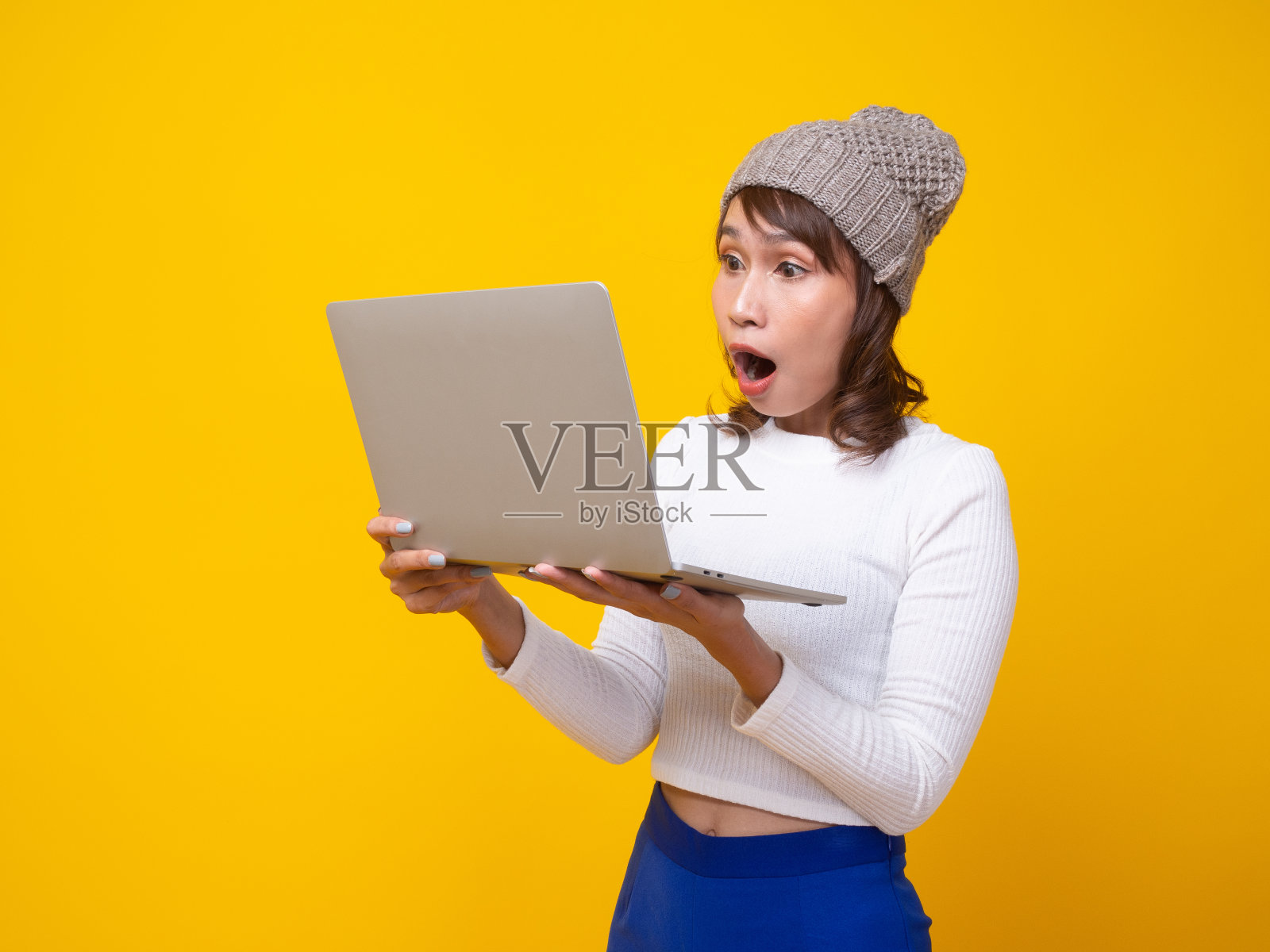 The woman was shocked and staring at the laptop held in her hand.照片摄影图片