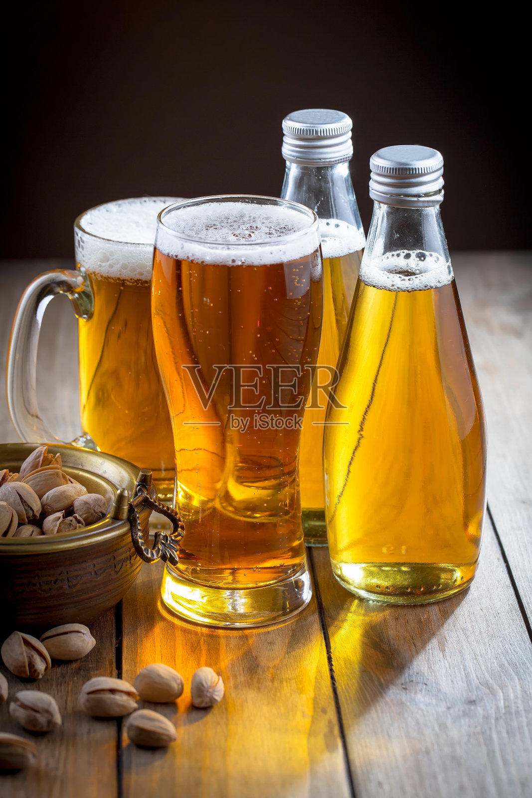 木背景上的玻璃杯里装着淡啤酒。照片摄影图片