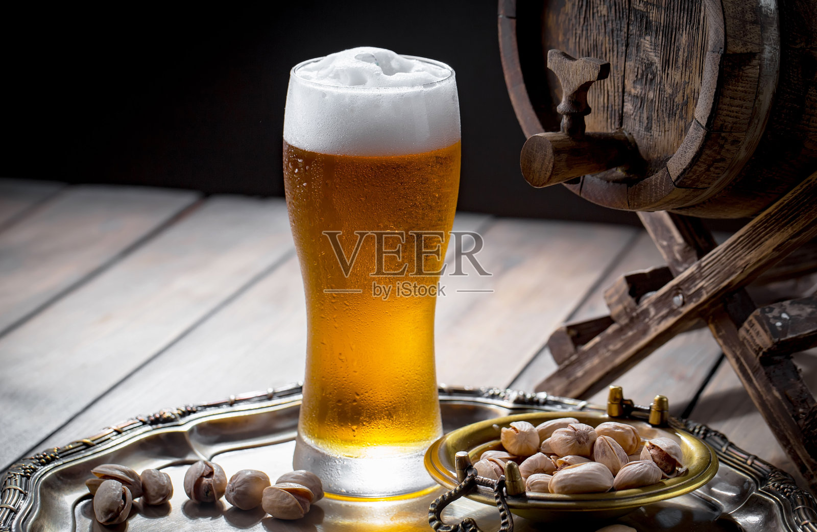 木背景上的玻璃杯里装着淡啤酒。照片摄影图片