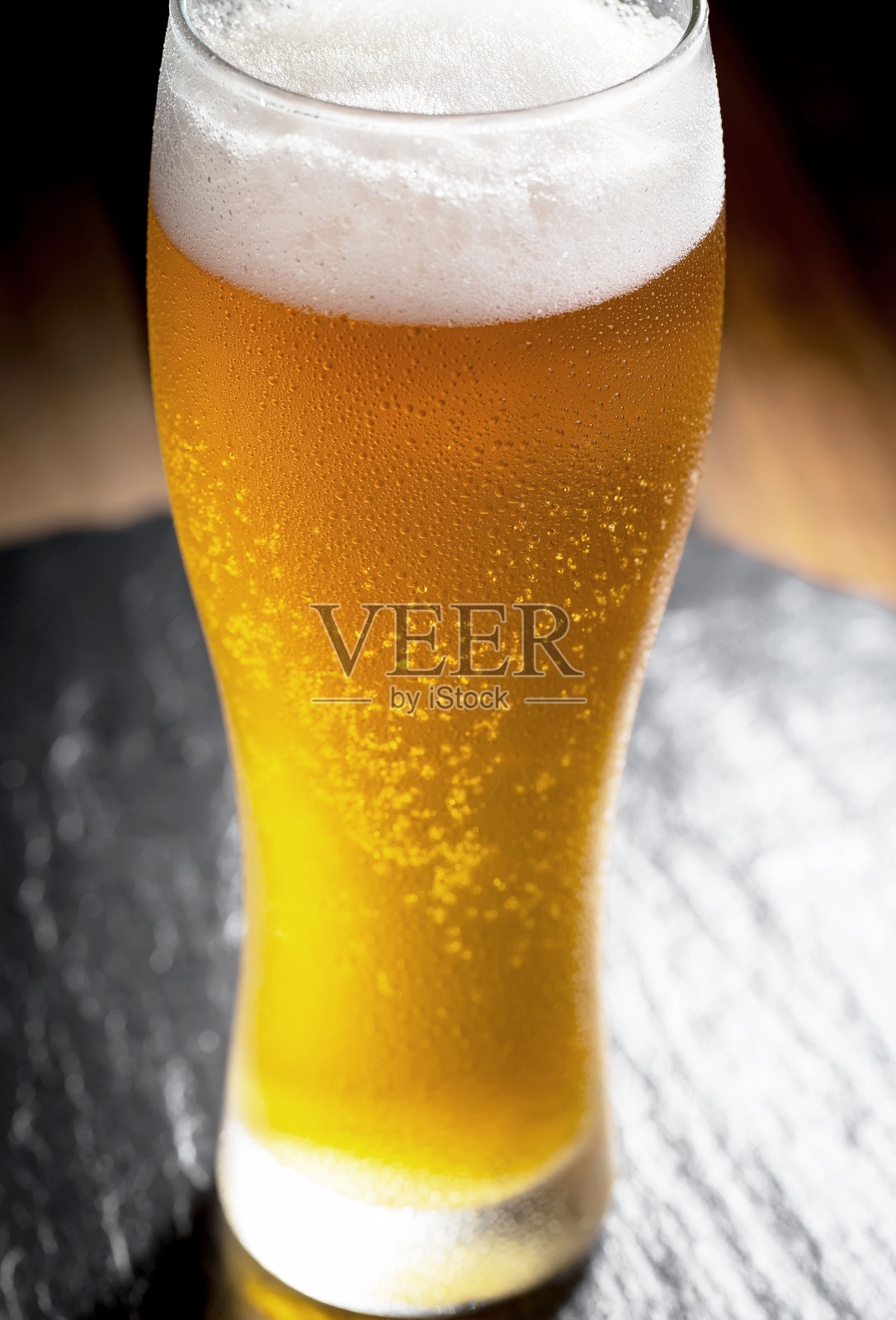 木背景上的玻璃杯里装着淡啤酒。照片摄影图片