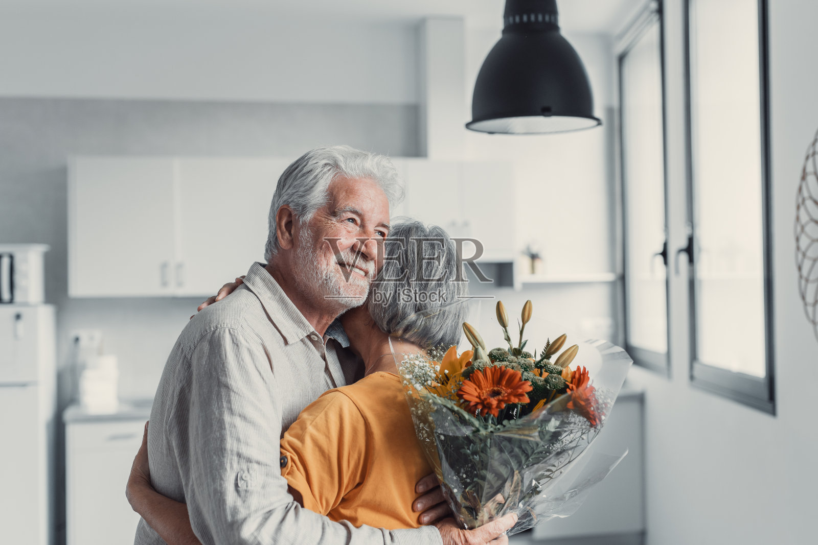 情人节这天，一位老人向坐在家里沙发上的妻子献花。养老金领取者一起享受惊喜。在爱情中，人们有乐趣。照片摄影图片