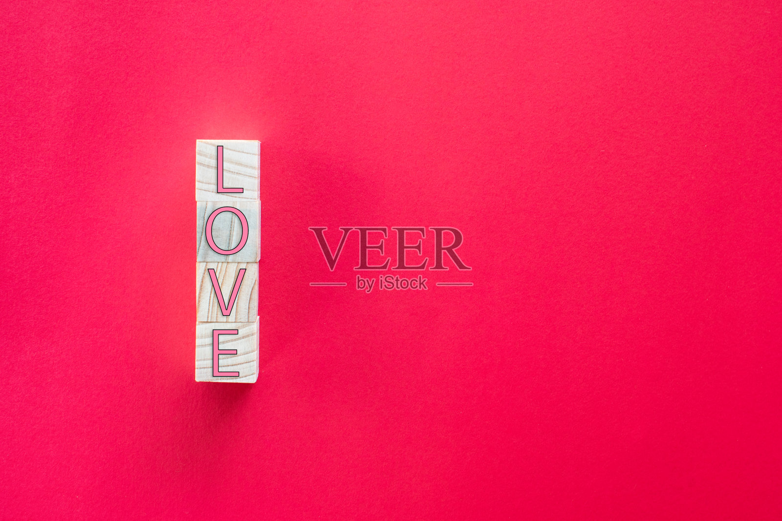 拍一张特写。木质立方体上的“LOVE”字母垂直排列在红色背景上。情人节的概念照片摄影图片