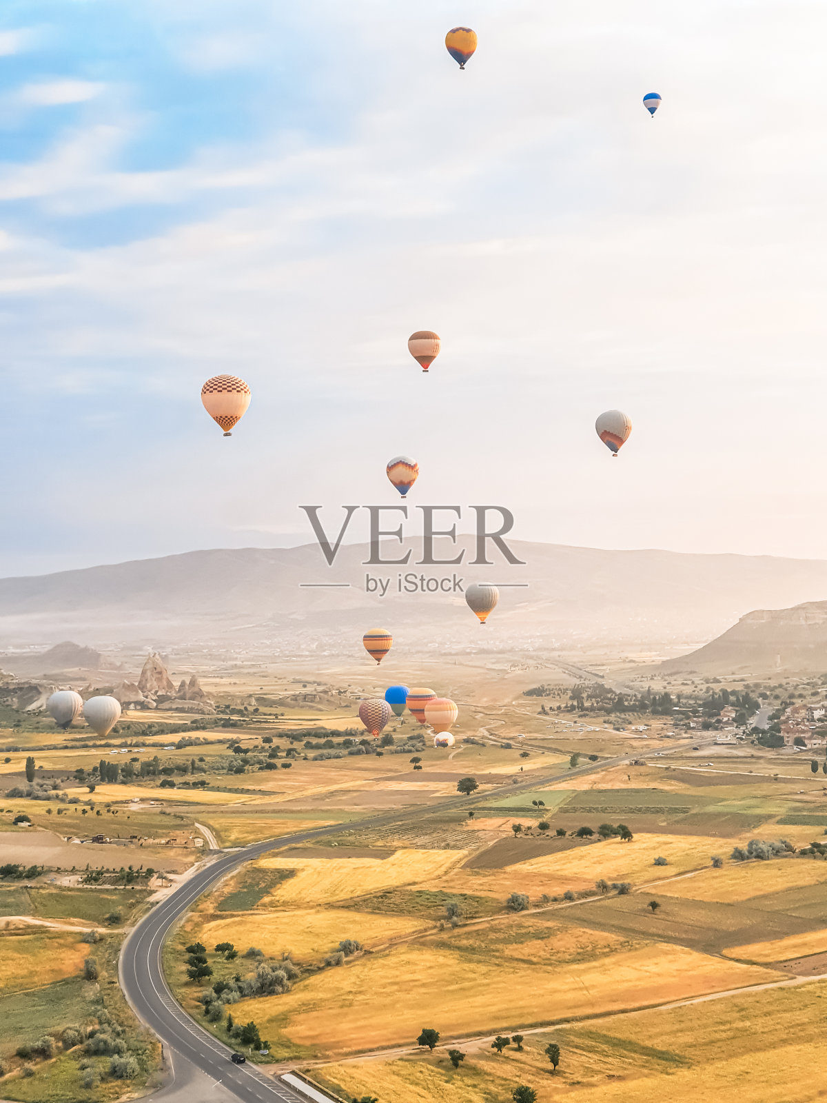 天空中飞着许多色彩鲜艳的美丽的气球，在卡帕多西亚的山上，日出、黎明时分飞向空中。用燃烧器，大篮子里的热空气填充气球。游客游览，云游飞翔照片摄影图片