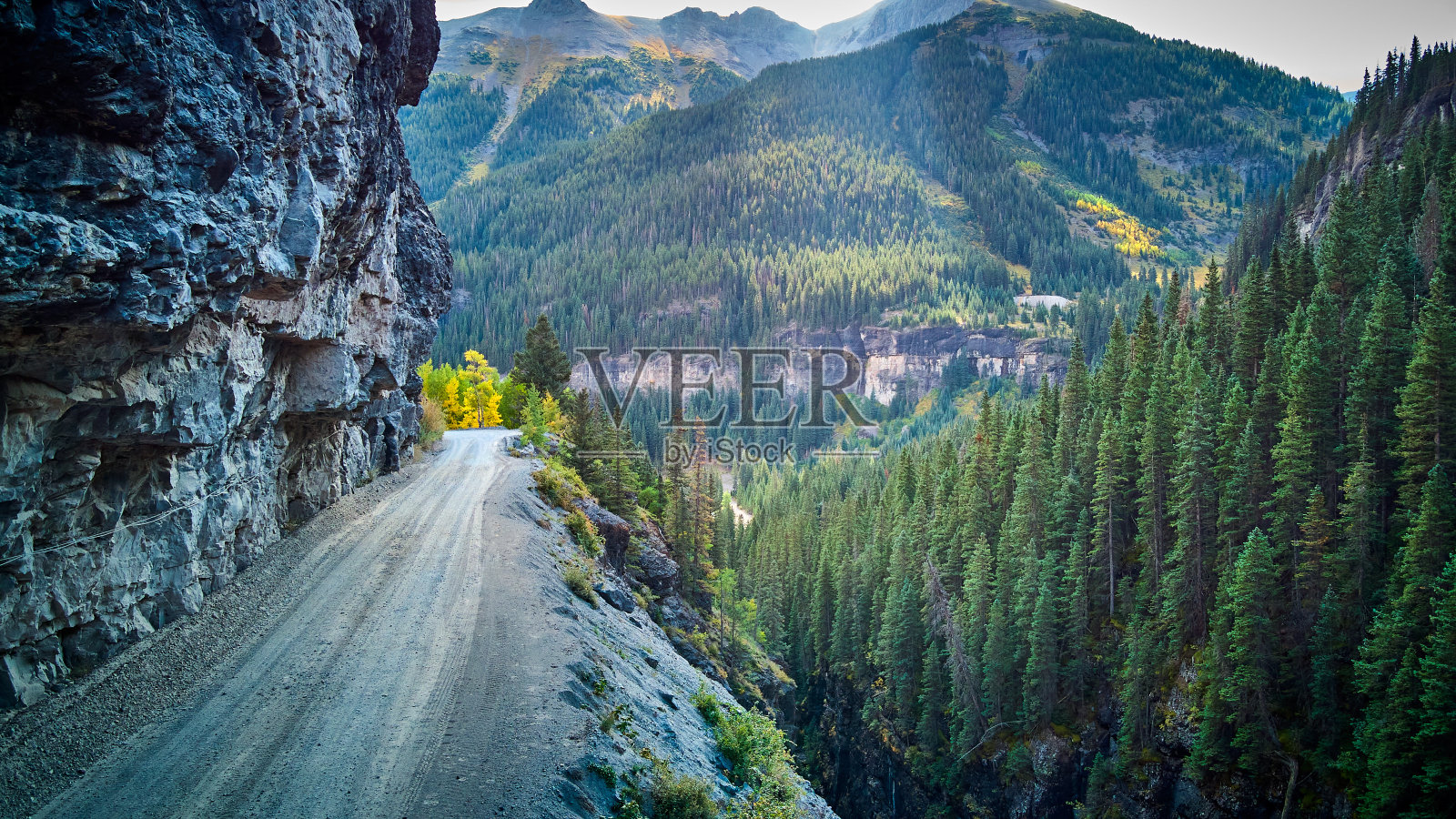危险的土路在落基山脉狭窄的悬崖边缘在山谷的山脉照片摄影图片