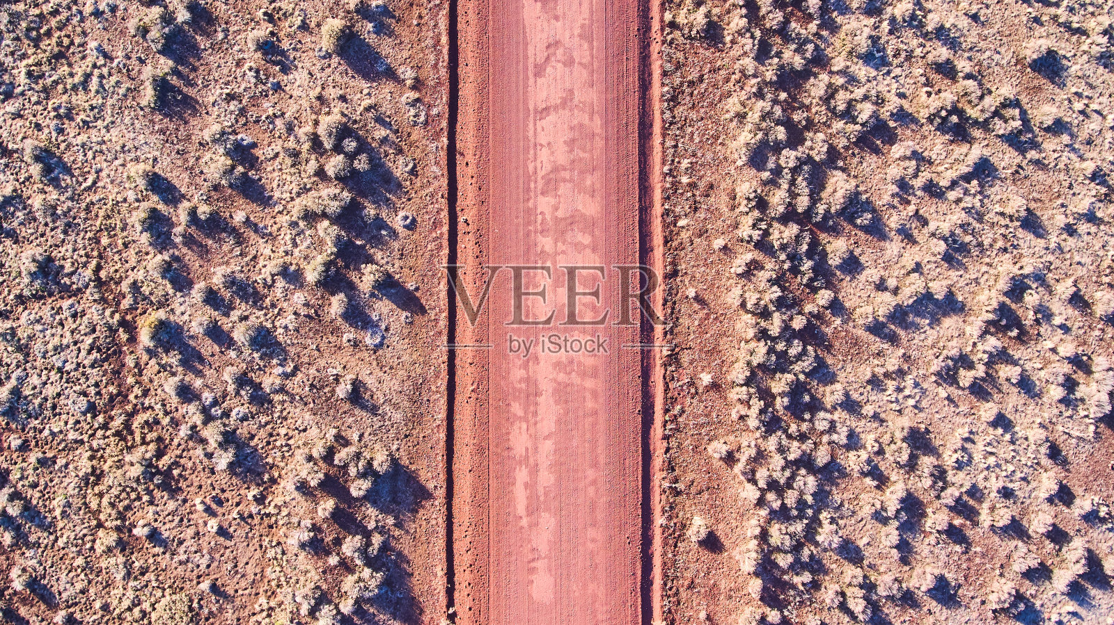 从空中俯瞰平原上的红沙沙漠道路照片摄影图片