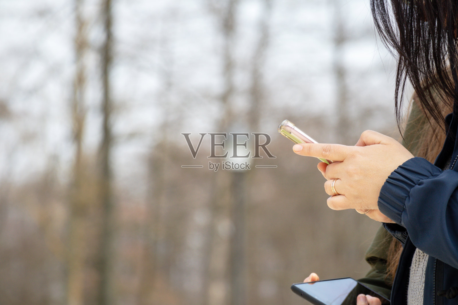 一个女人拿着手机看着她的手机。照片摄影图片