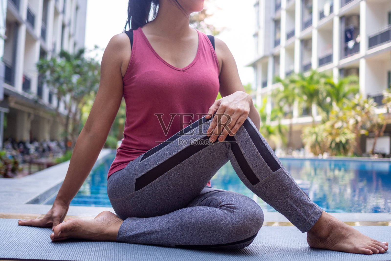 亚洲女性穿着运动服，瑜伽，扭转姿势，泳池边放松健康的运动理念。照片摄影图片