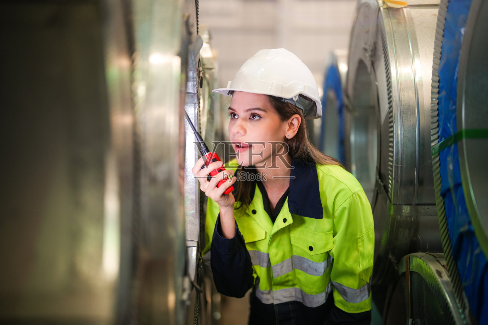 女工程师在仓库检查和检查钢角色材料。聪明的工业工人在操作。在工厂拿金属板的工业维修工程师。照片摄影图片
