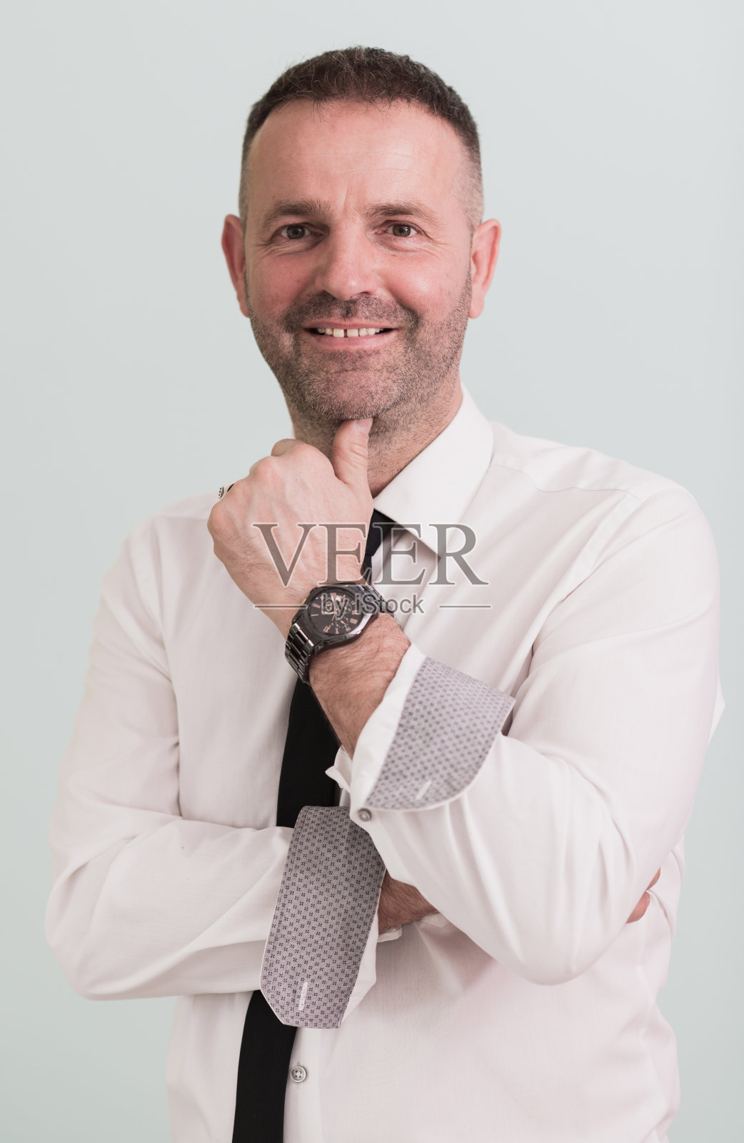 穿着正式职业装的休闲商人对着镜头微笑，双手交叉在灰色背景上。照片摄影图片