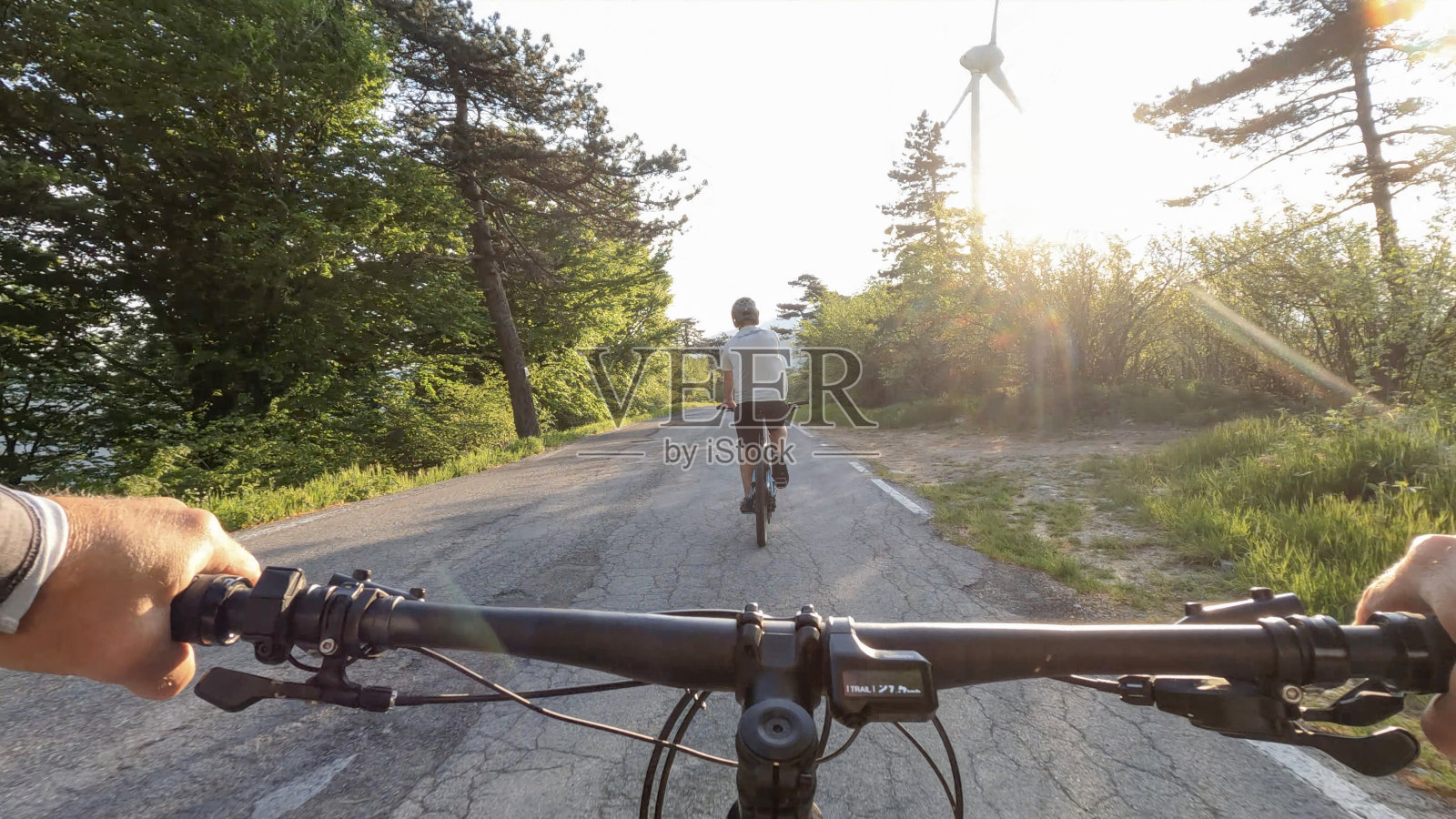 第一人称视角跟踪前面的男性摩托车手，风力涡轮机照片摄影图片