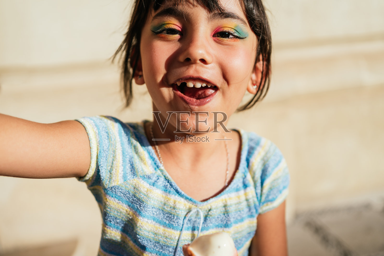 孩子笑着看着镜头，手里拿着冰淇淋。照片摄影图片