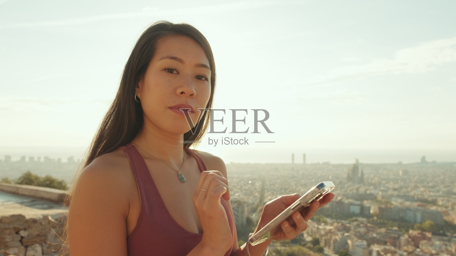 年轻女子用手机看相机的手特写，背光照片摄影图片