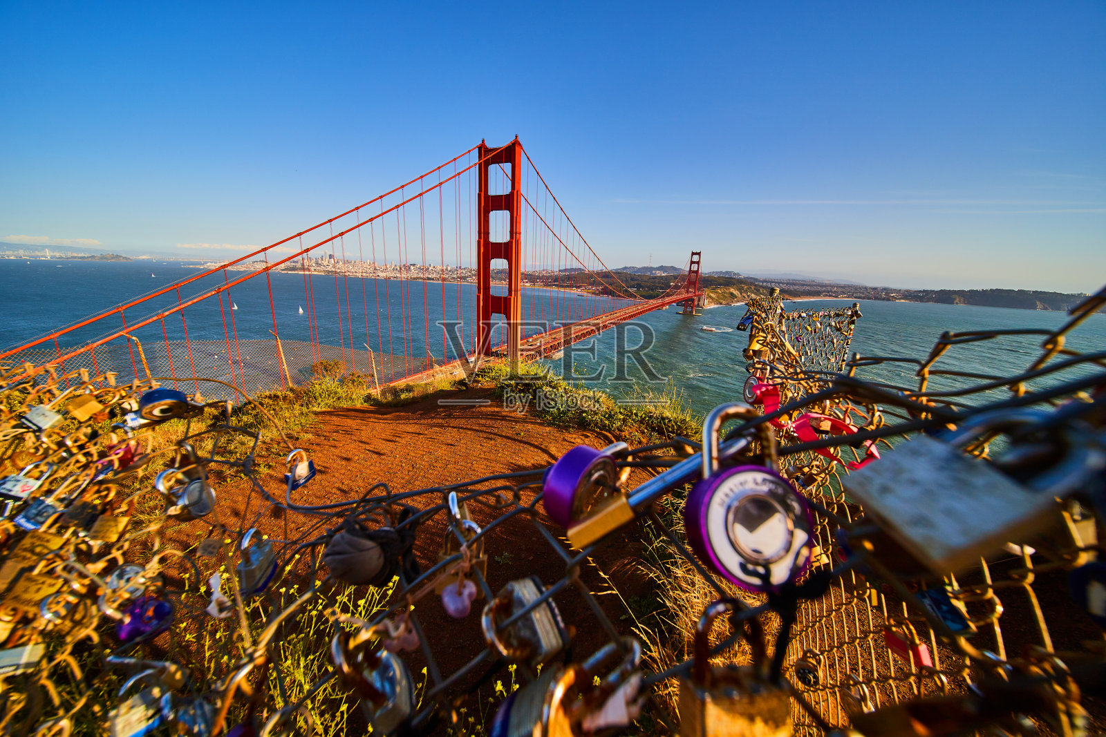 夕阳下的金门大桥，前景是被数百个锁覆盖的栅栏照片摄影图片