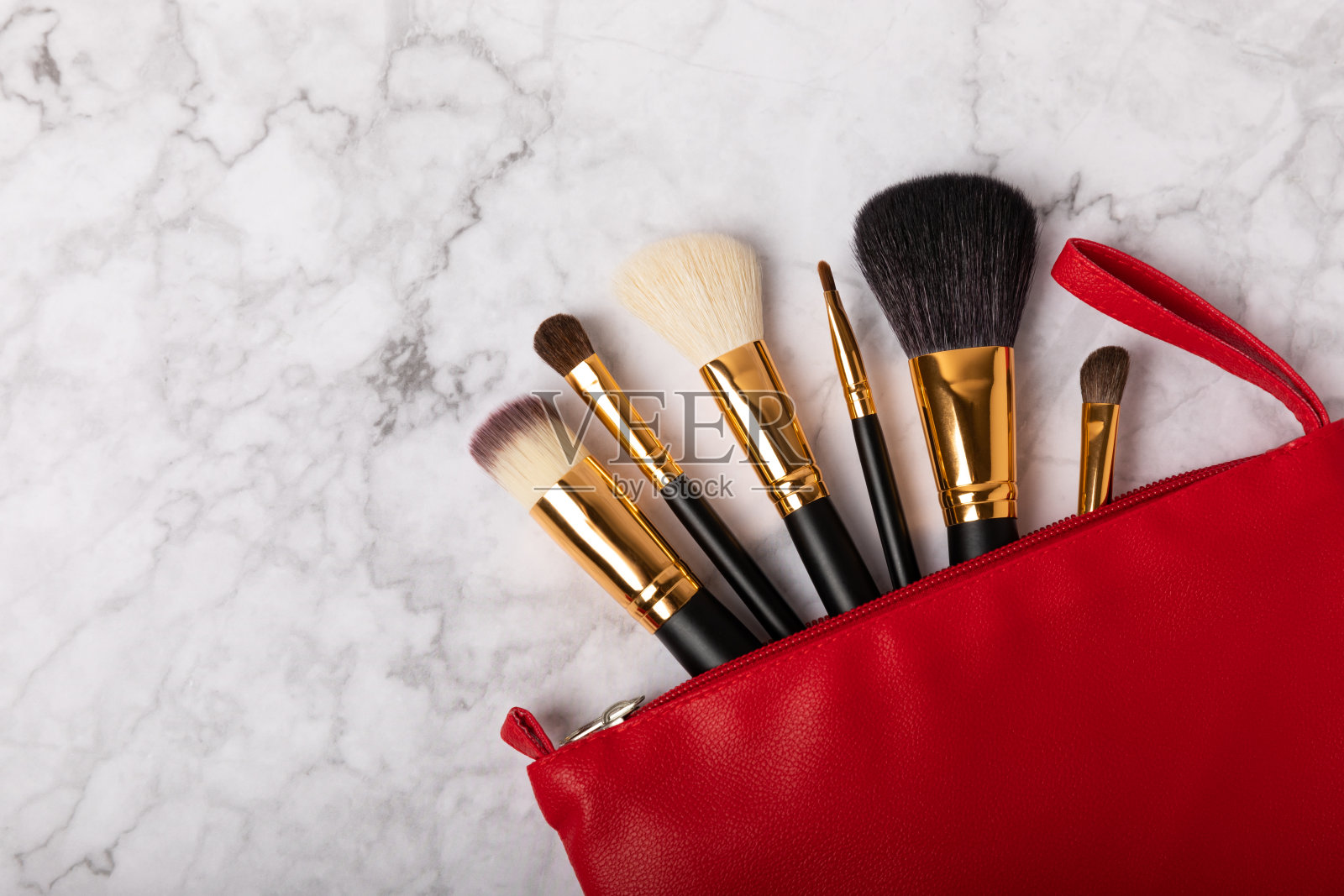 化妆用的化妆品。化妆刷装在白色大理石背景上的红色化妆袋里。创意时尚理念。化妆刷的集合，俯视图，横幅。平的。照片摄影图片