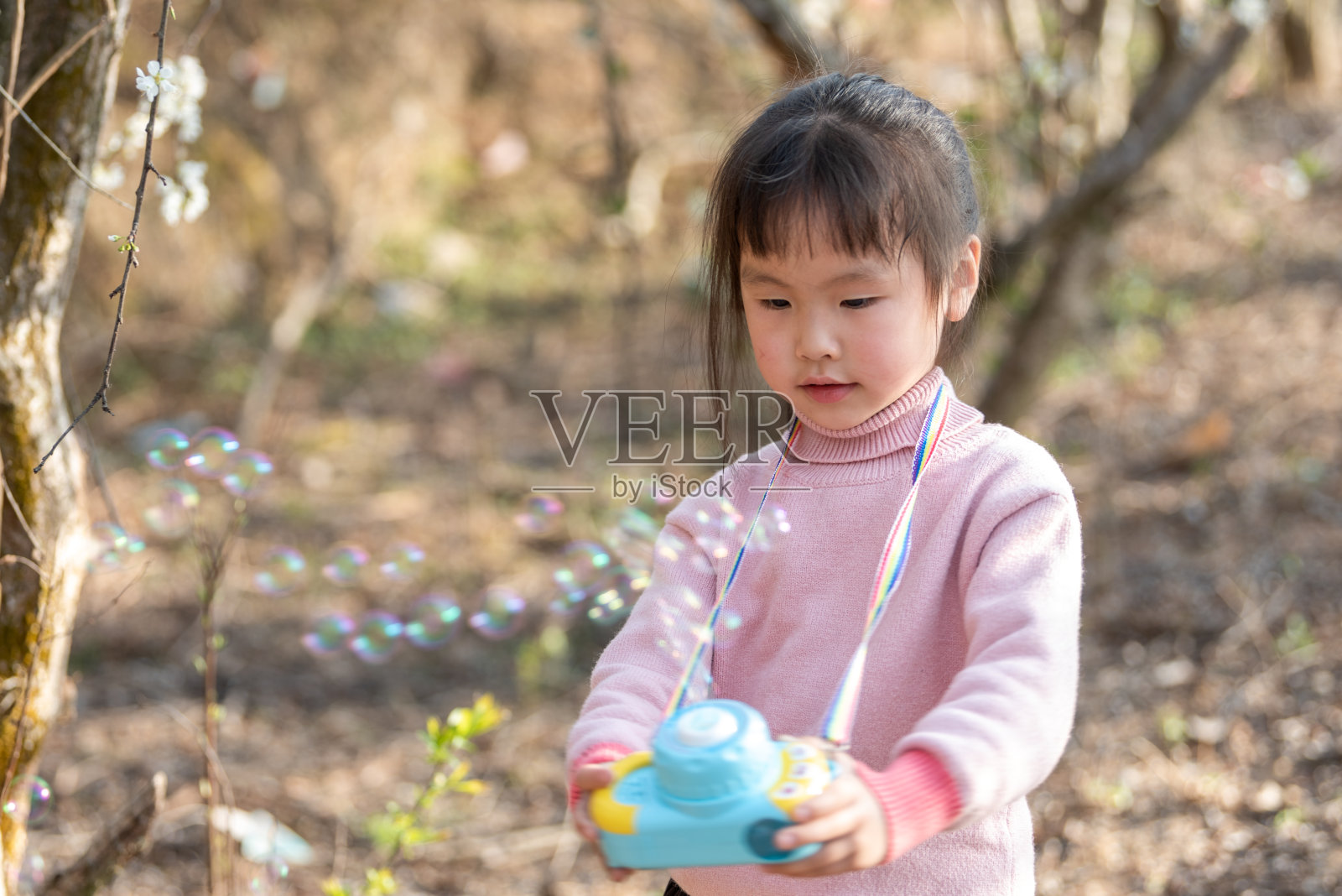 一个小女孩在盛开的梅树上吹泡泡照片摄影图片