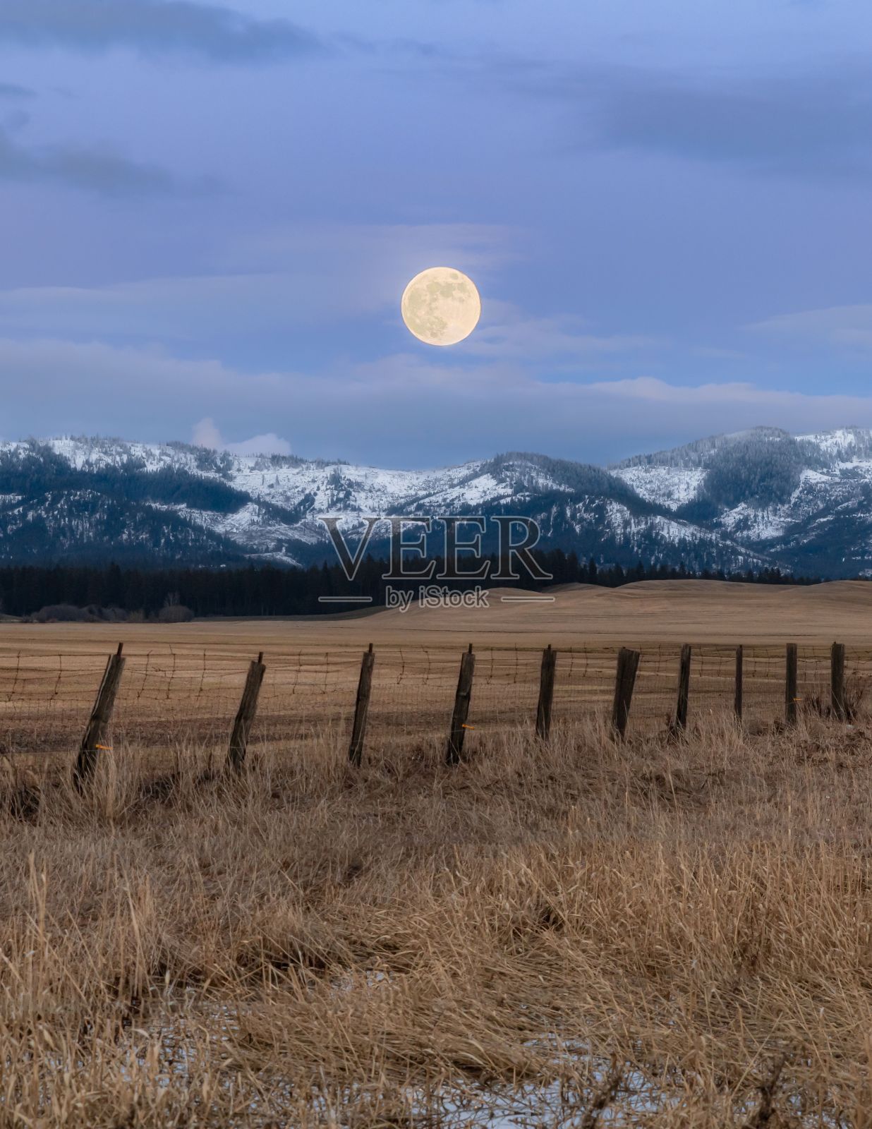 月亮落在有栅栏的雪景上照片摄影图片