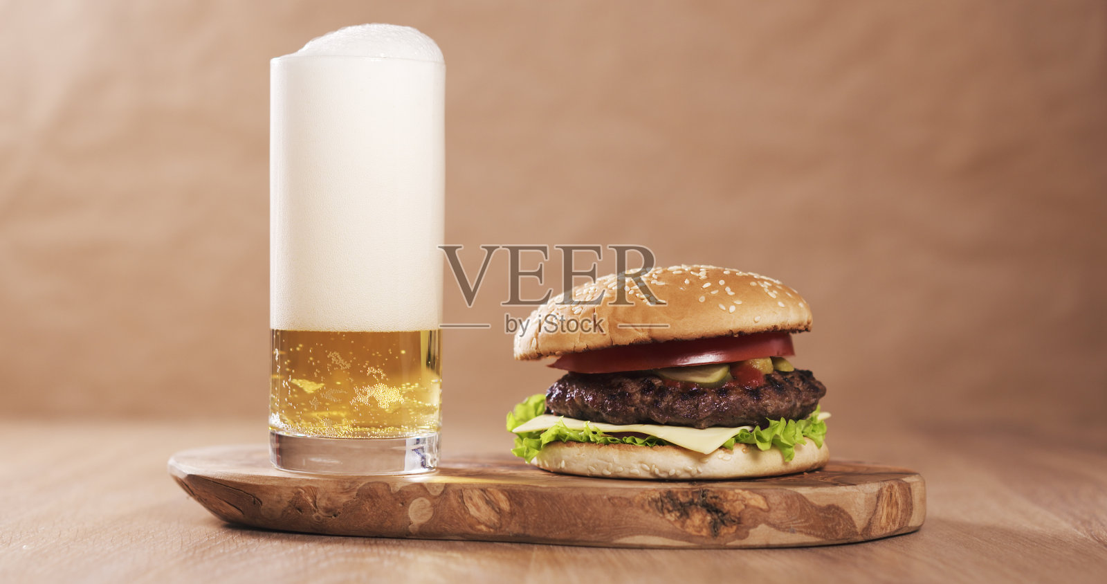 自制汉堡，配以大理石牛肉、甜洋葱、奶酪和蔬菜，配以淡啤酒照片摄影图片