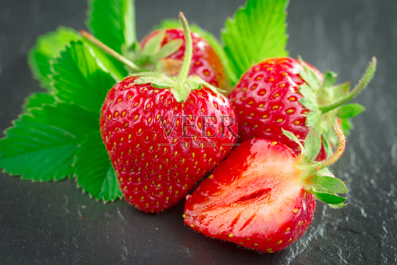 桌上有带叶子的草莓。照片摄影图片