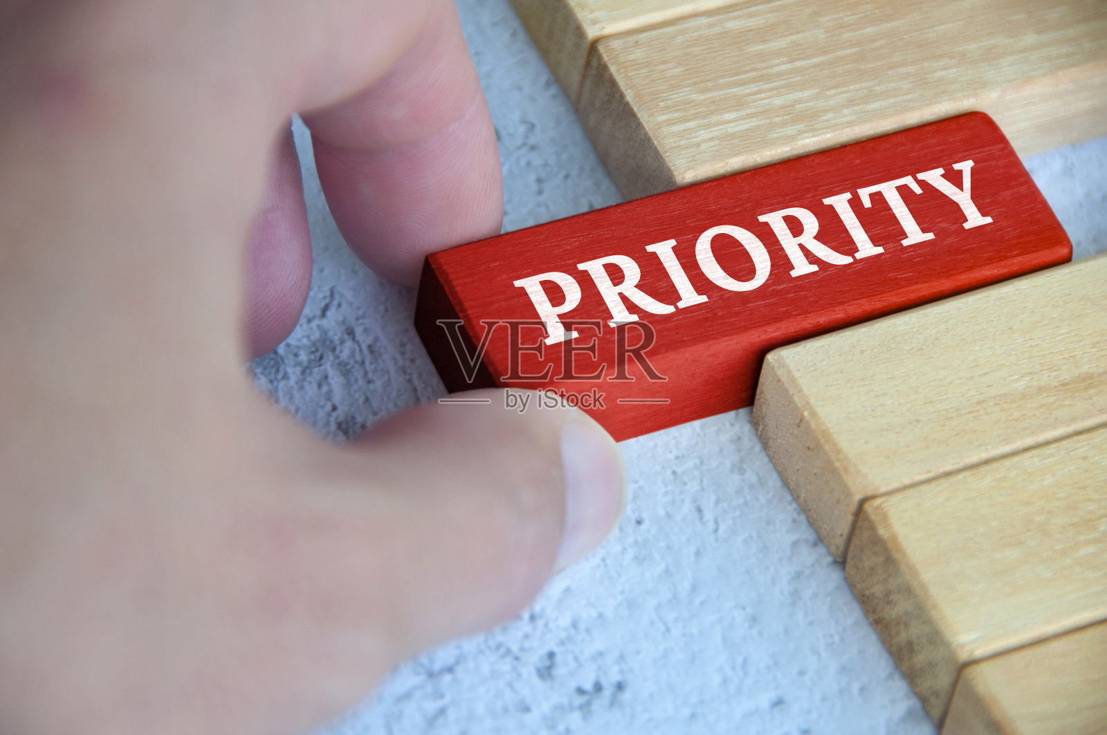 用手放置带有文字的红色木块-优先级。优先级和经营理念照片摄影图片