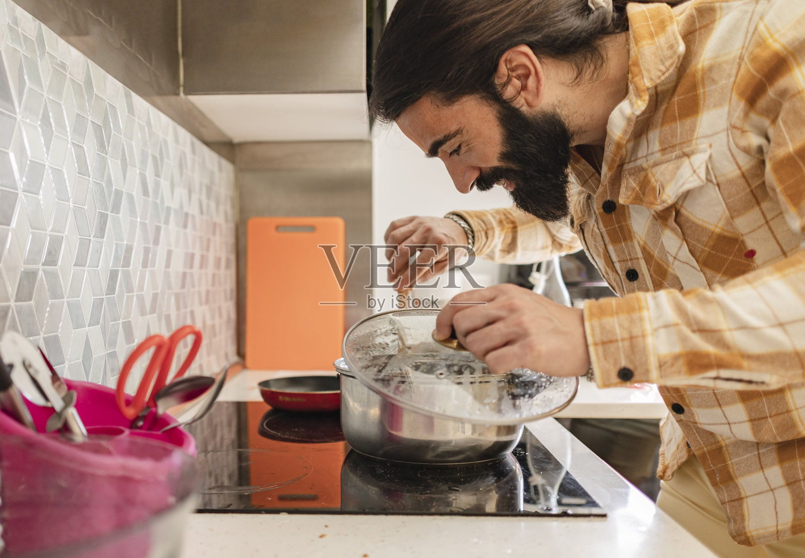 大胡子中年男子正在家里的厨房里准备好吃的饭菜照片摄影图片