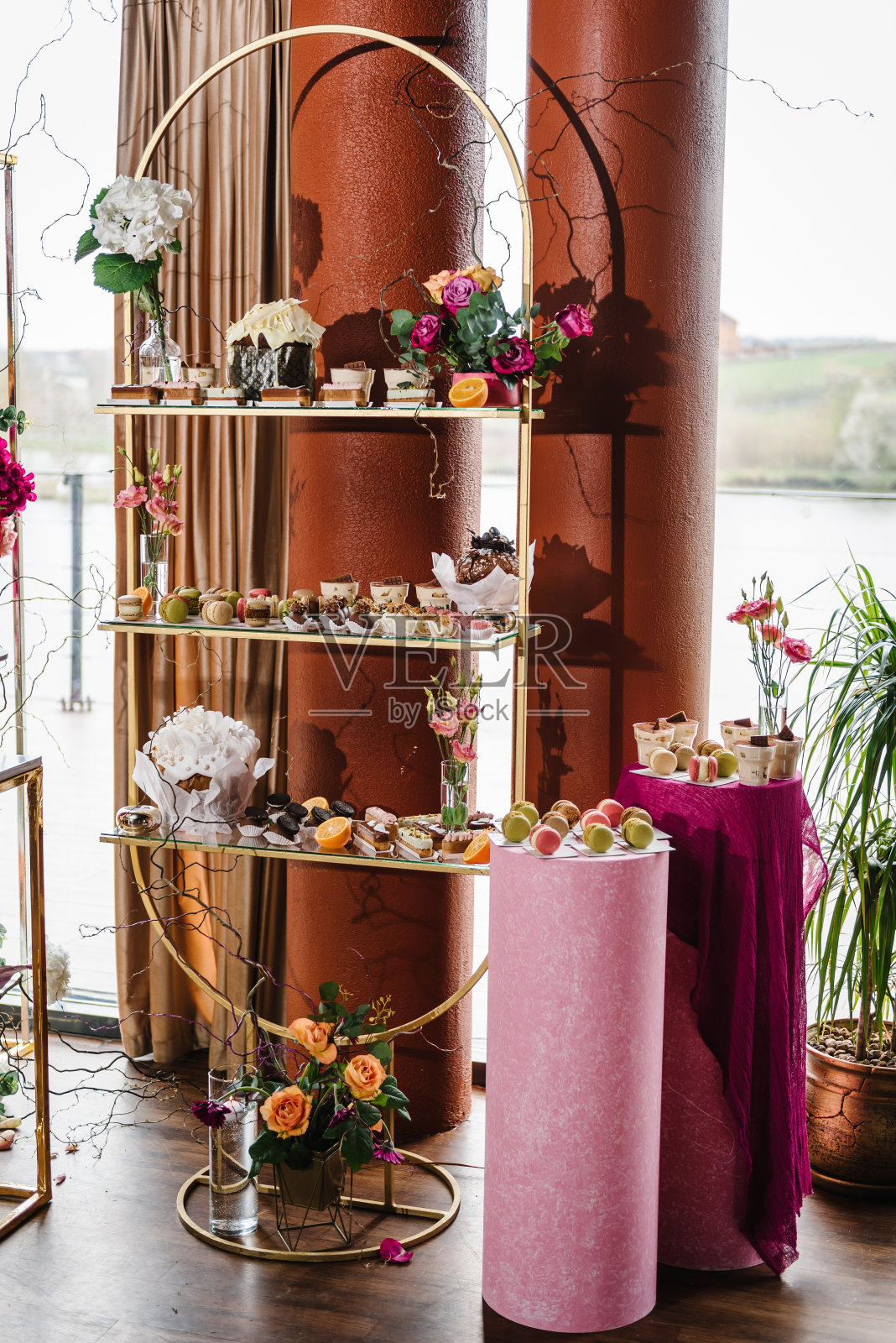 美味的婚宴豪华的仪式。背景装饰。糖果酒吧。桌上摆满了糖果、糖果、甜点。拱门装饰粉红色，橙花玫瑰为生日宴会区，大厅。照片摄影图片