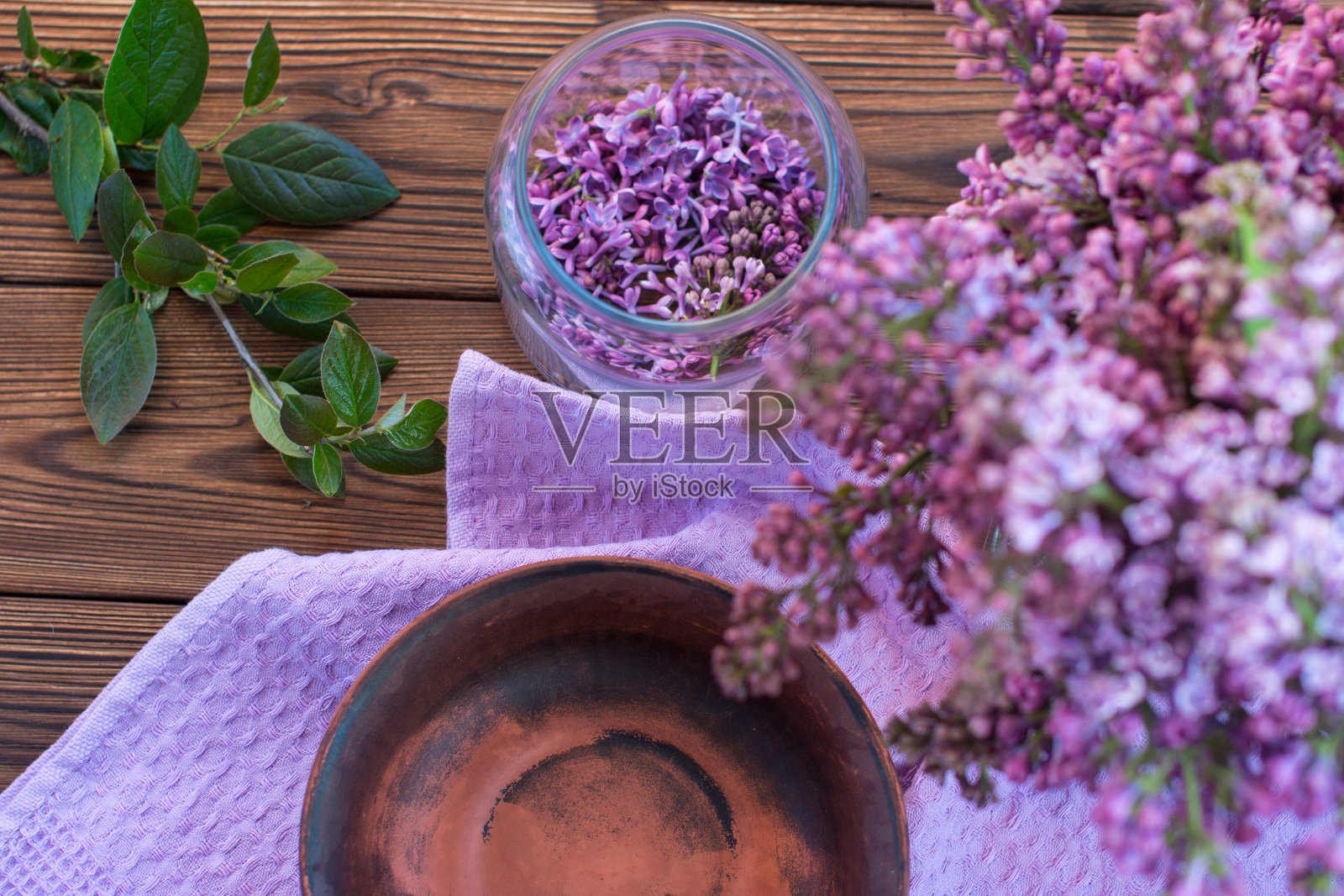 木制背景花瓶里的一束紫丁香。为生产香油而对花进行干燥照片摄影图片