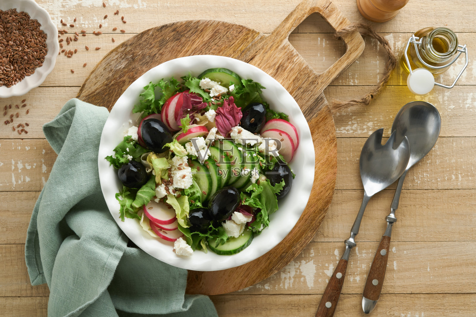 生菜沙拉，黄瓜，萝卜沙拉，奶酪和亚麻籽橄榄油沙拉在旧木背景。健康的减肥食品。饮食菜单和均衡饮食。前视图。照片摄影图片