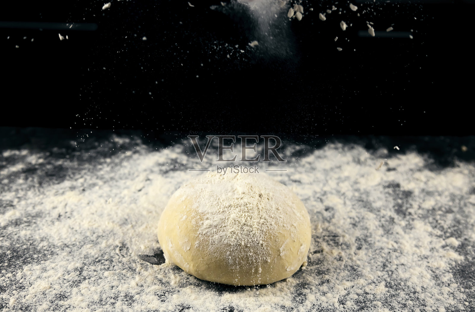 生面团撒上面粉在黑色背景上。做面包或披萨的面团照片摄影图片