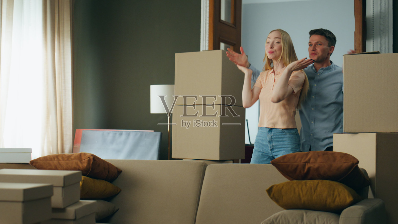 丈夫给妻子一个进入新家的惊喜。一对夫妇在包装好的箱子旁拥抱照片摄影图片
