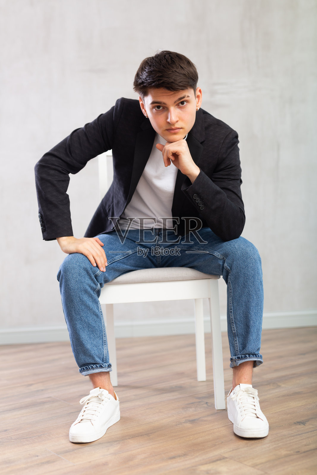 有魅力的年轻人坐在房间中央的椅子上照片摄影图片