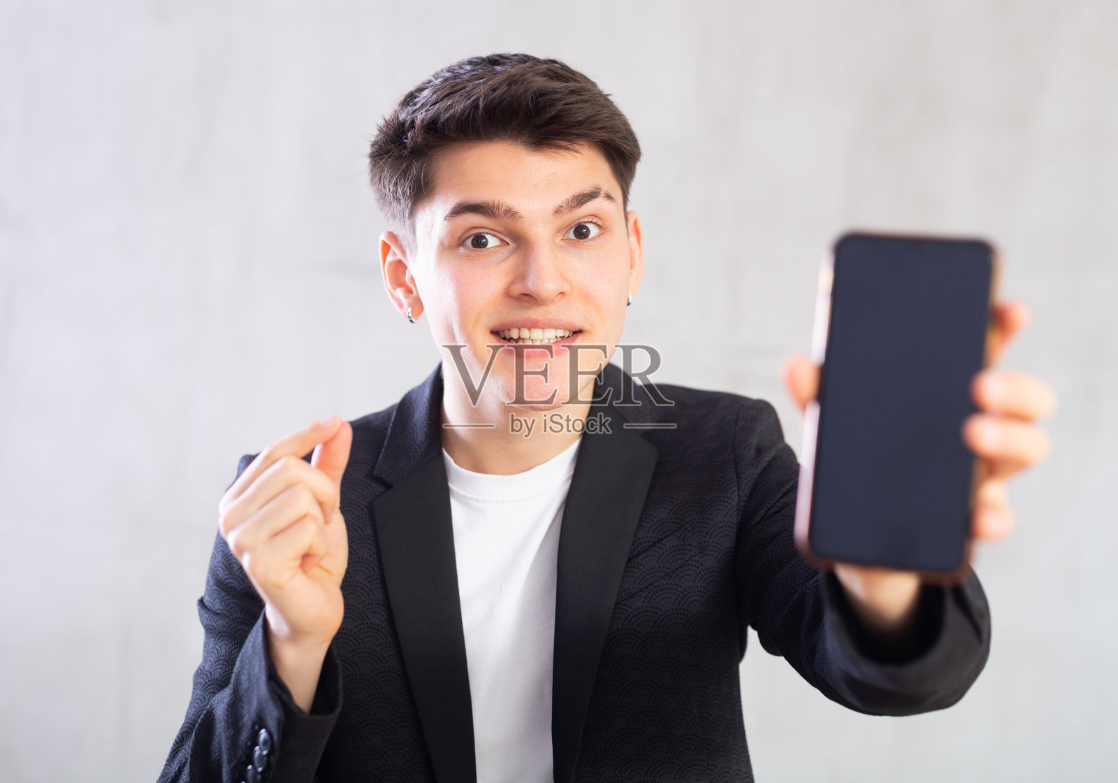 身穿黑色西装外套的特工展示着漆黑的手机屏幕，并用手指着设备照片摄影图片