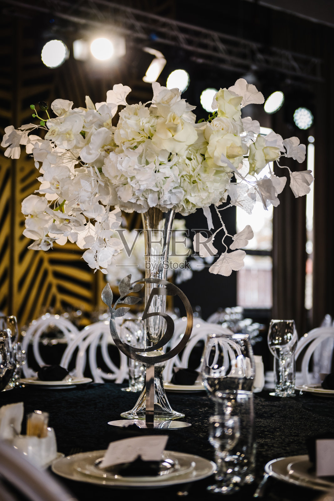 表5。布置和服务客人的特写镜头。起立，5号手势。特写镜头。婚礼布置细节。喜庆的餐桌上铺着黑色桌布，在宴会区装饰着构图花卉。照片摄影图片