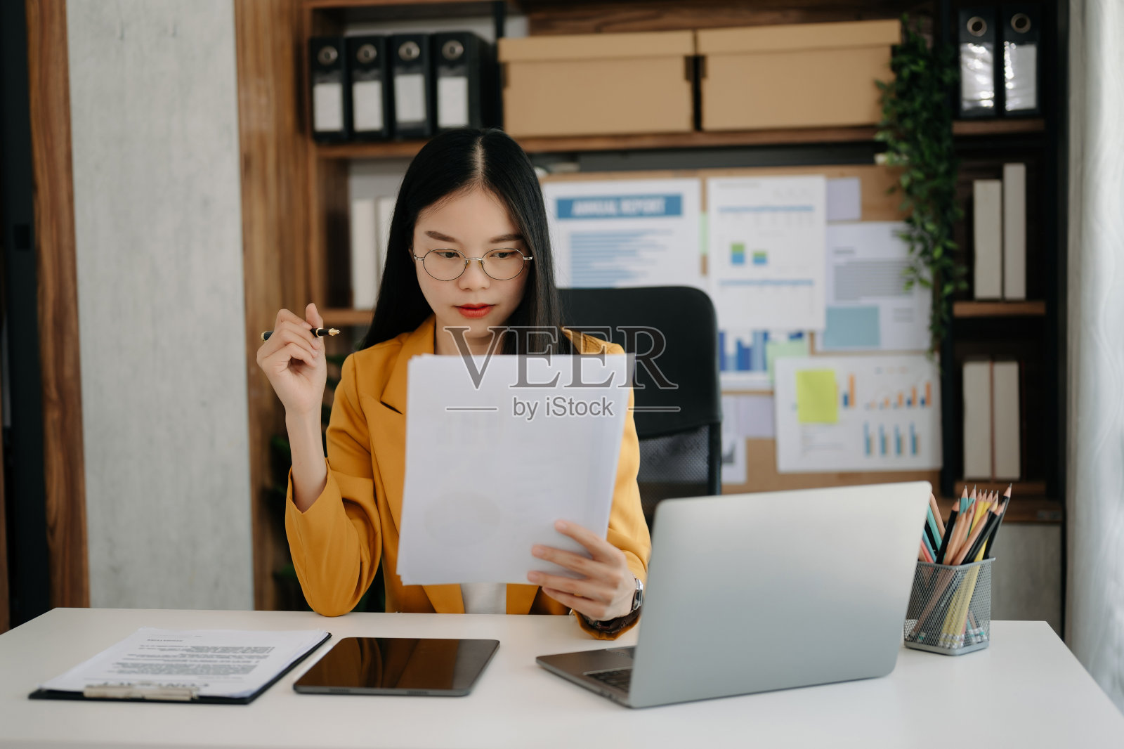 在办公室工作的亚洲商务女性，在办公室使用工作记事本，平板电脑和笔记本电脑照片摄影图片