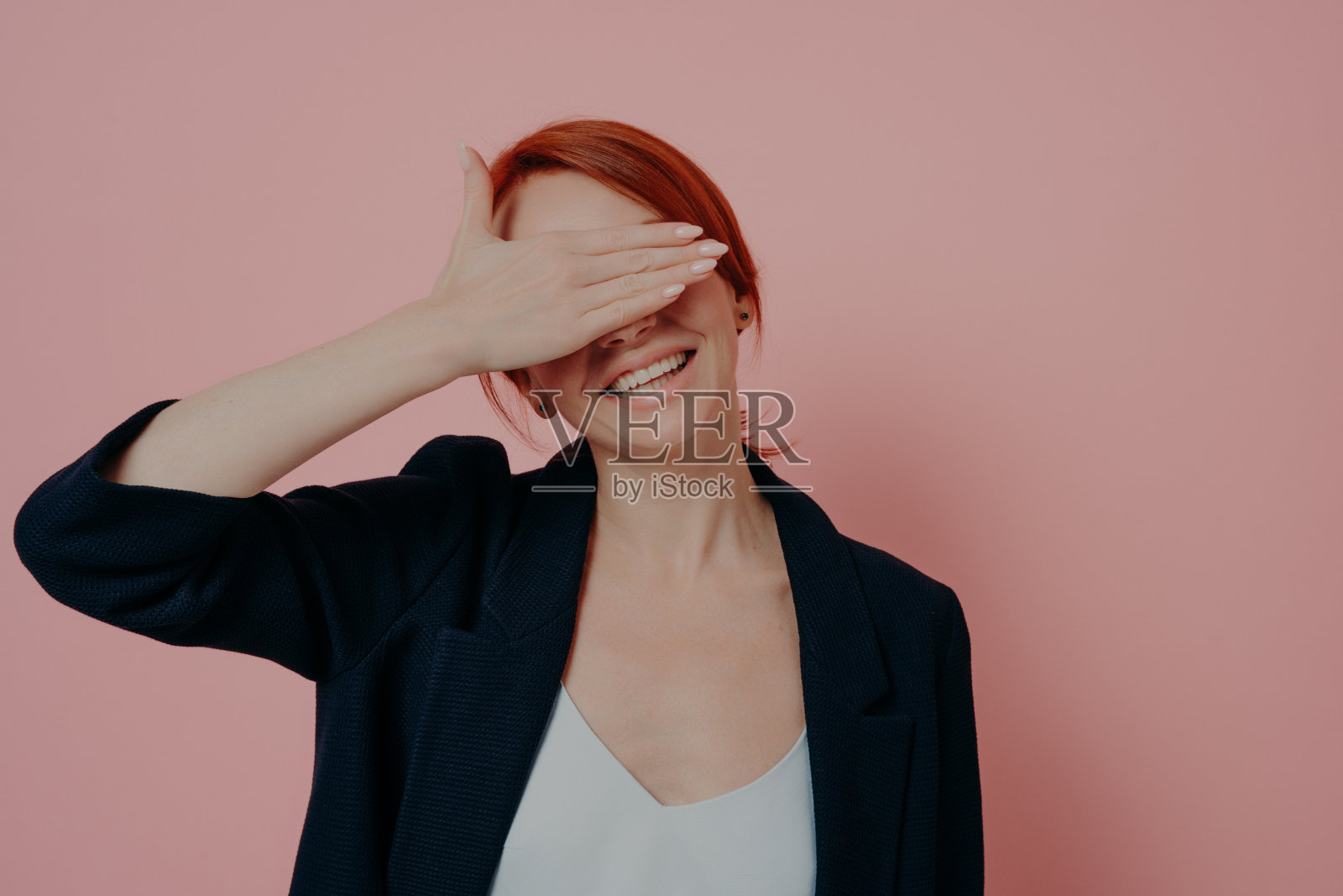 积极快乐的姜黄色女孩在时尚的服装孤立在粉红色的背景下玩捉迷藏照片摄影图片