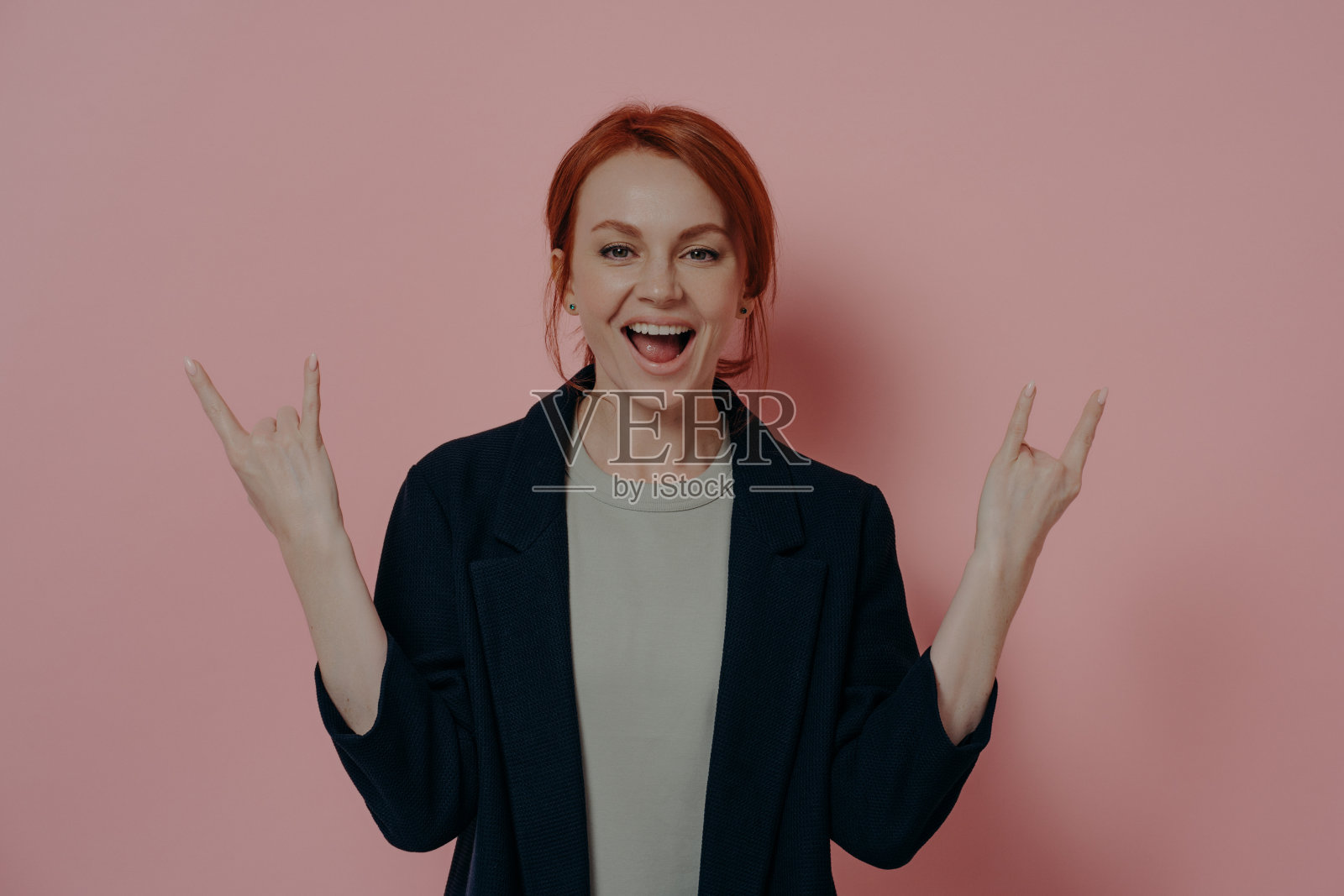 疯狂的红发欧洲女人，有犄角的迹象，摇滚的手势照片摄影图片