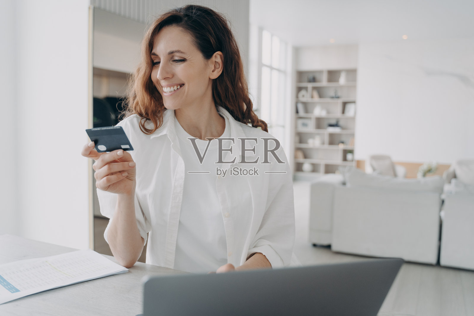 快乐的欧洲女孩拿着信用卡去网上购物。通过互联网购买。照片摄影图片