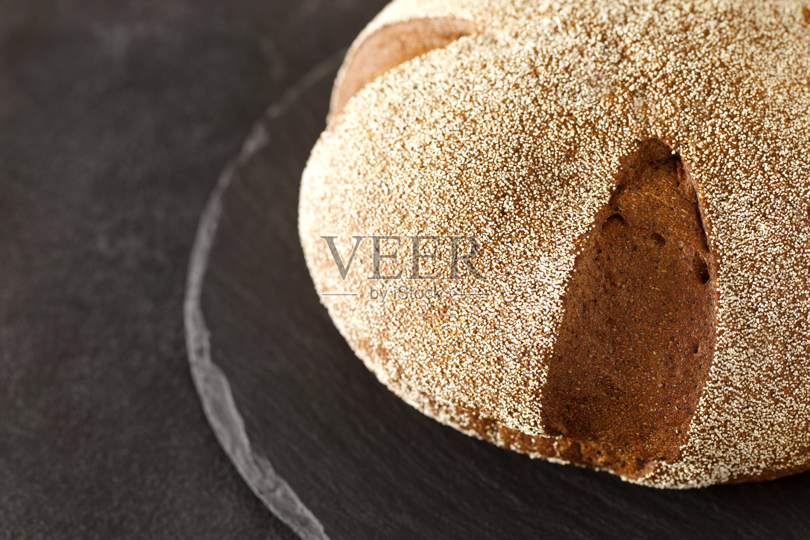 黑圆面包上撒着小麦粉，在石板石盘上圆润，选择性聚焦照片摄影图片