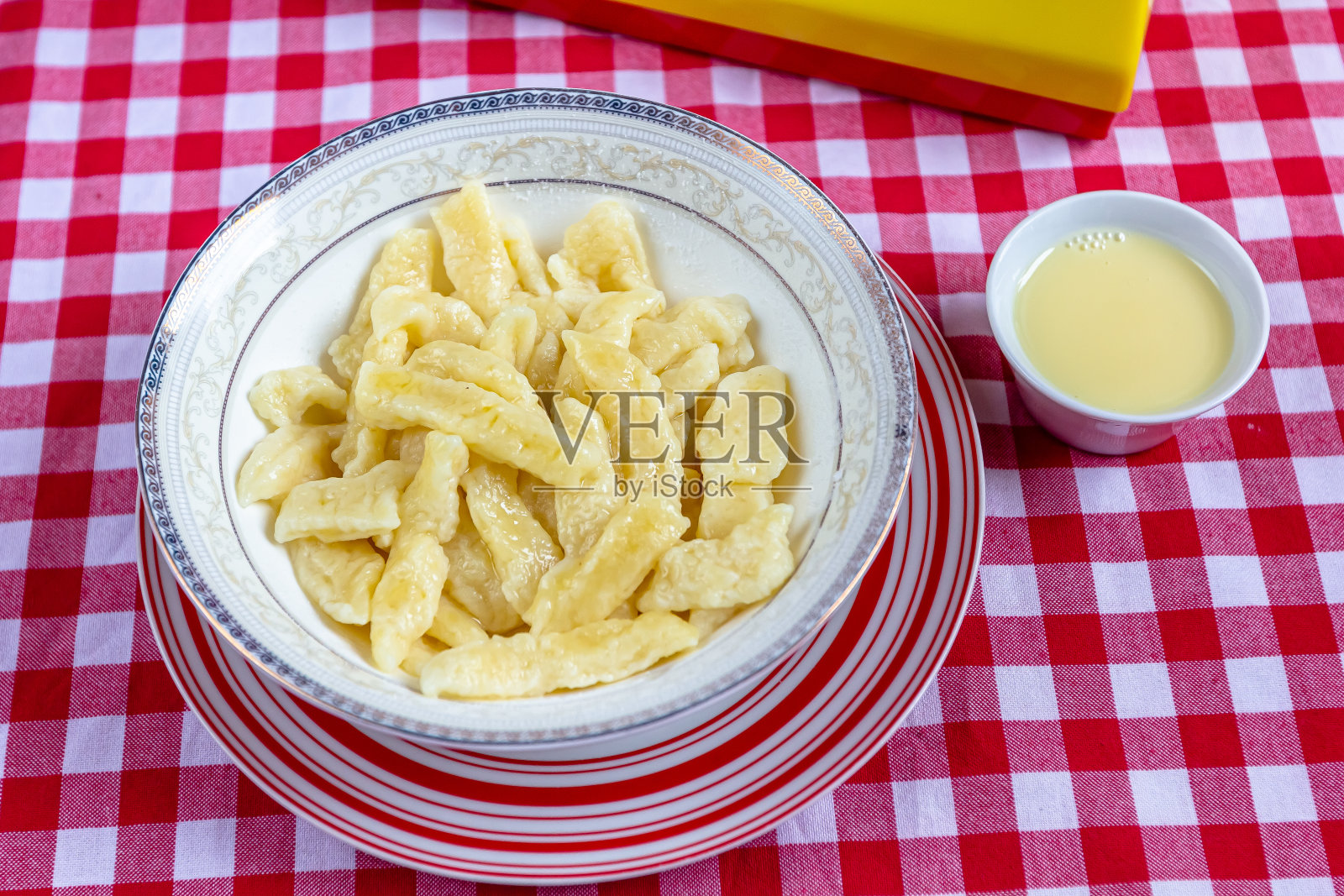 俄罗斯和乌克兰美食。在浅灰色的背景上，白色的盘子里放着慵懒的饺子，里面有糖、黄油和酸奶油。Flatlay，俯视图。背景图像，复制空间照片摄影图片