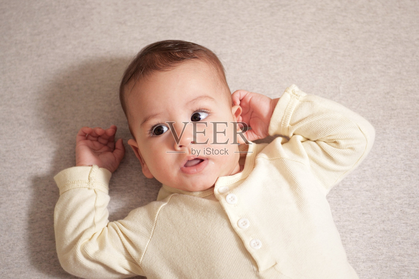 快乐的新生儿做了一个有趣的脸。一个在他房间里爬行的婴儿的肖像特写照片摄影图片