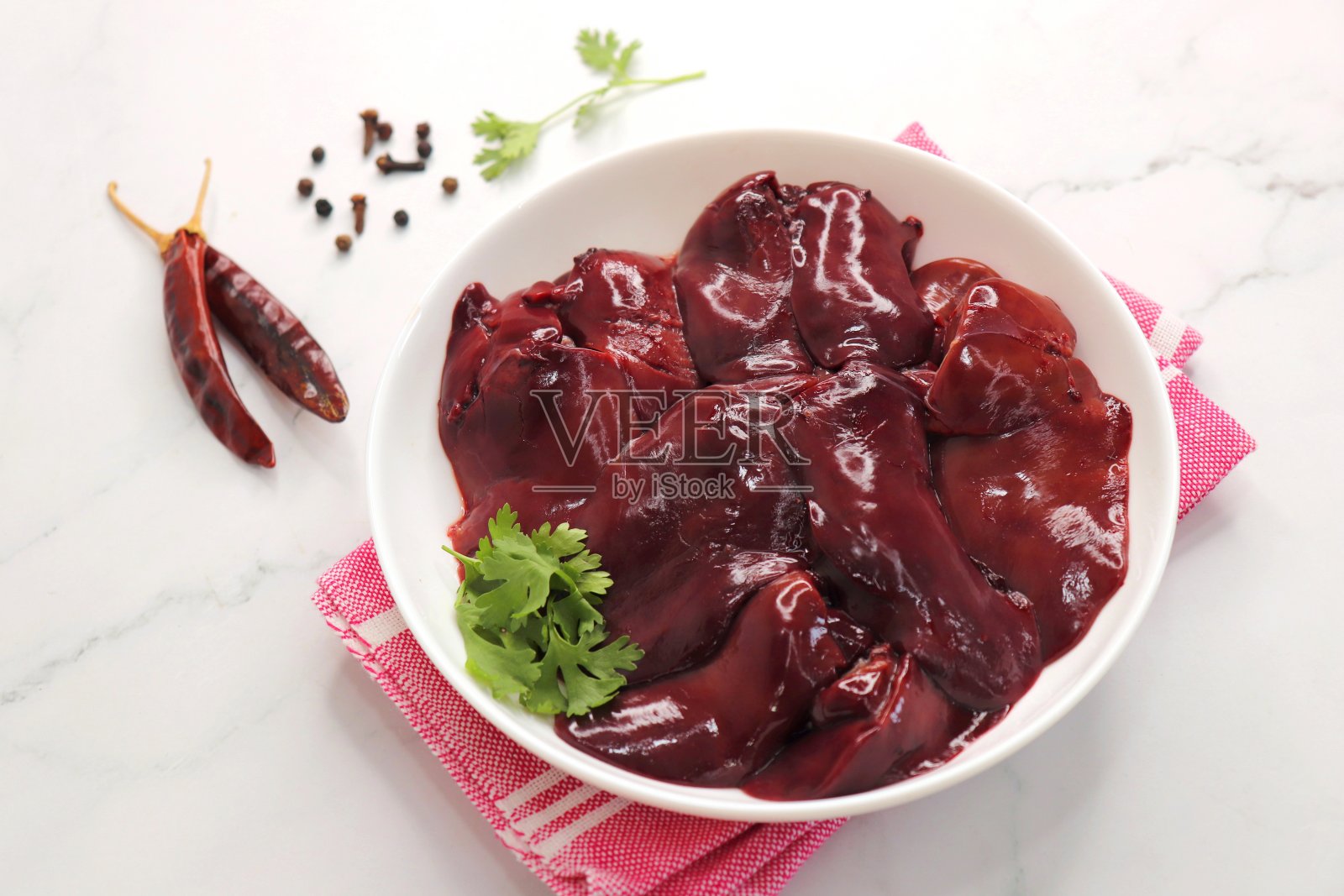 生鸡肝放在白色盘子里，配上大蒜、黑胡椒、青椒和香菜等香料。Kaleji。副本的空间。照片摄影图片