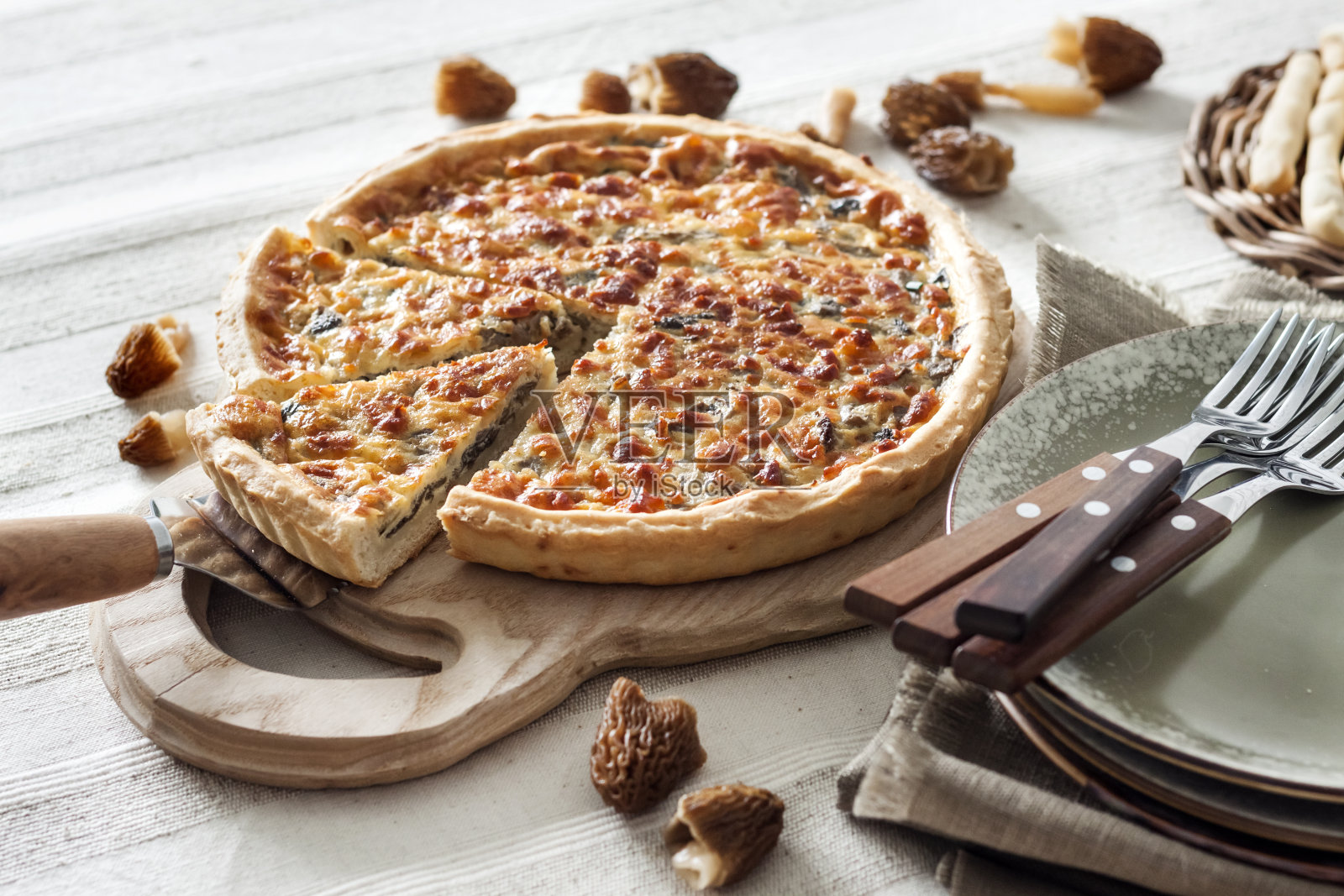 乳蛋饼——在砧板上切开的馅饼，配上羊肚菌、洋葱和奶酪照片摄影图片