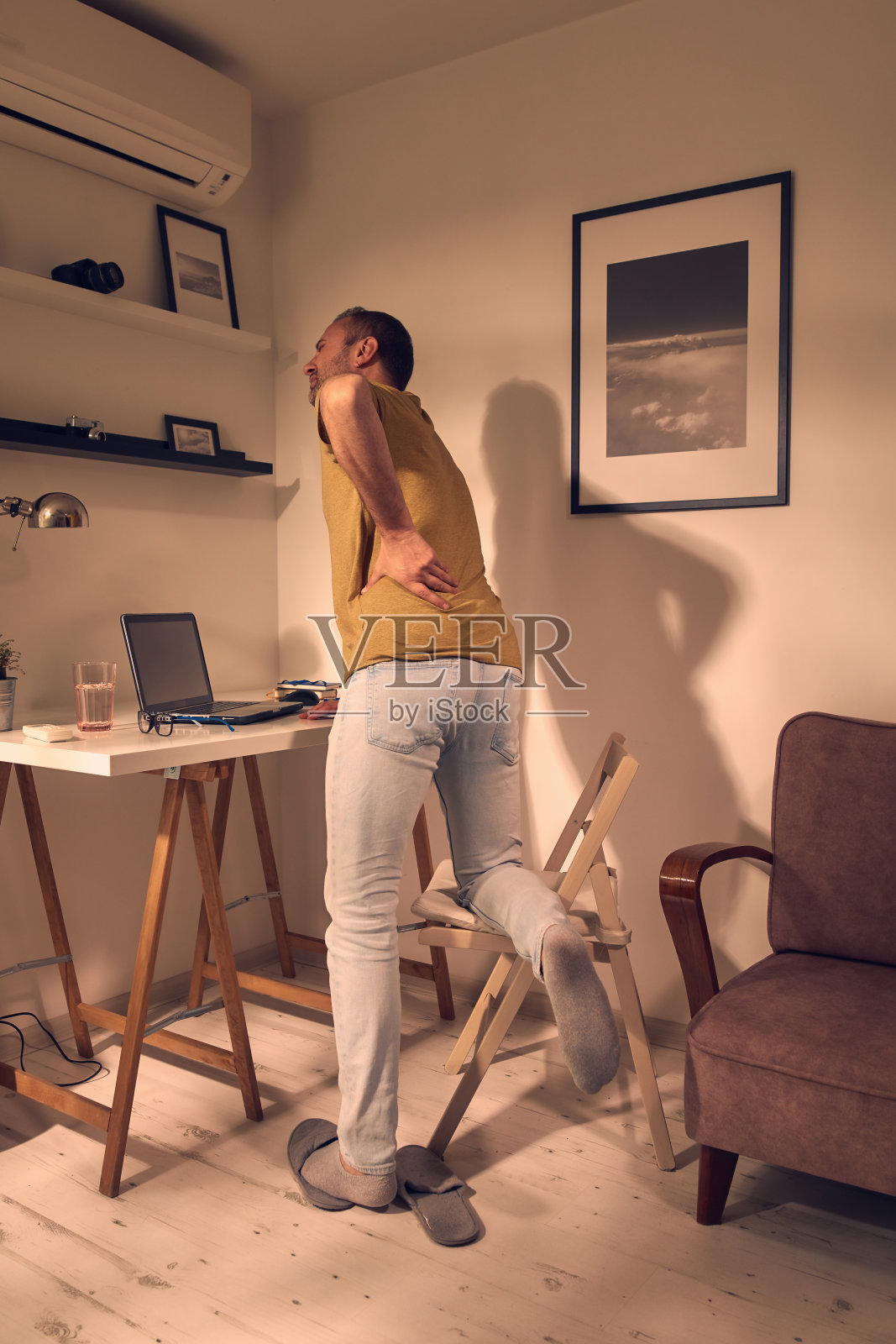 男人与臀部，背部，脊柱，疝和坐骨神经痛在家里。照片摄影图片