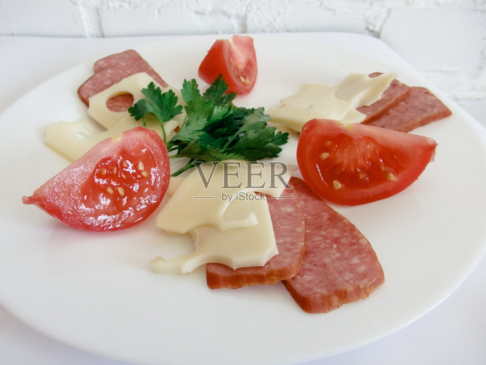 仍然生活。西红柿片，奶酪香肠，意大利腊肠，放在白色盘子里。光背景。照片摄影图片