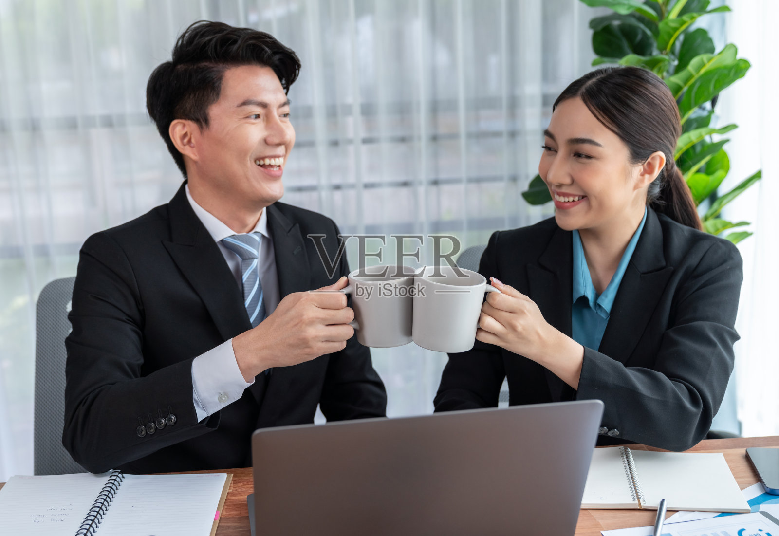 两个亚洲上班族在工作场所一起喝咖啡休息。欢欣鼓舞的照片摄影图片