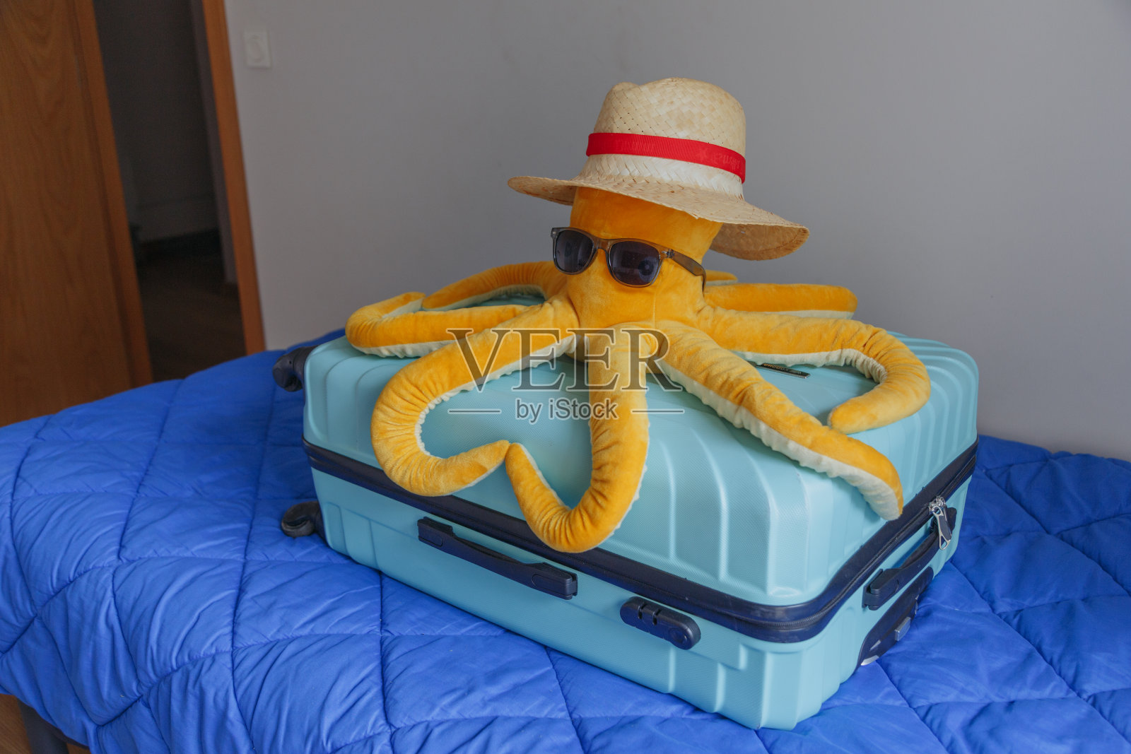 沙发上放着一只手提箱和一只海洋玩具章鱼。暑假照片摄影图片