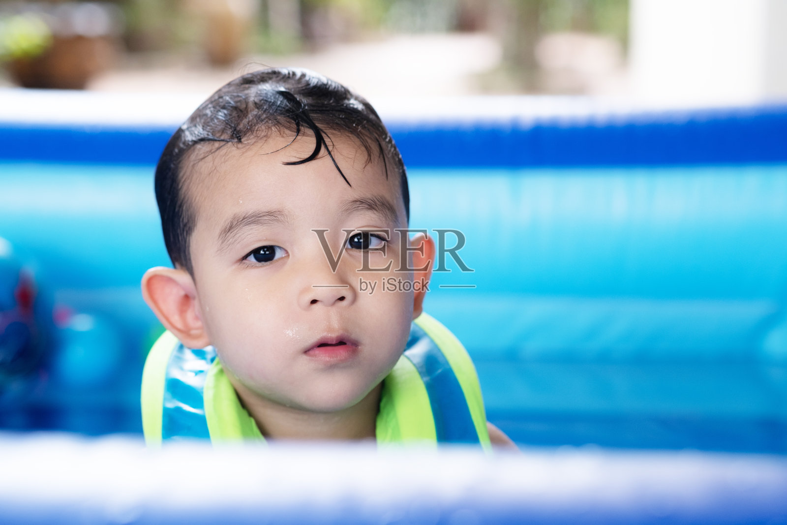 穿着救生衣的小男孩在泳池里玩水照片摄影图片