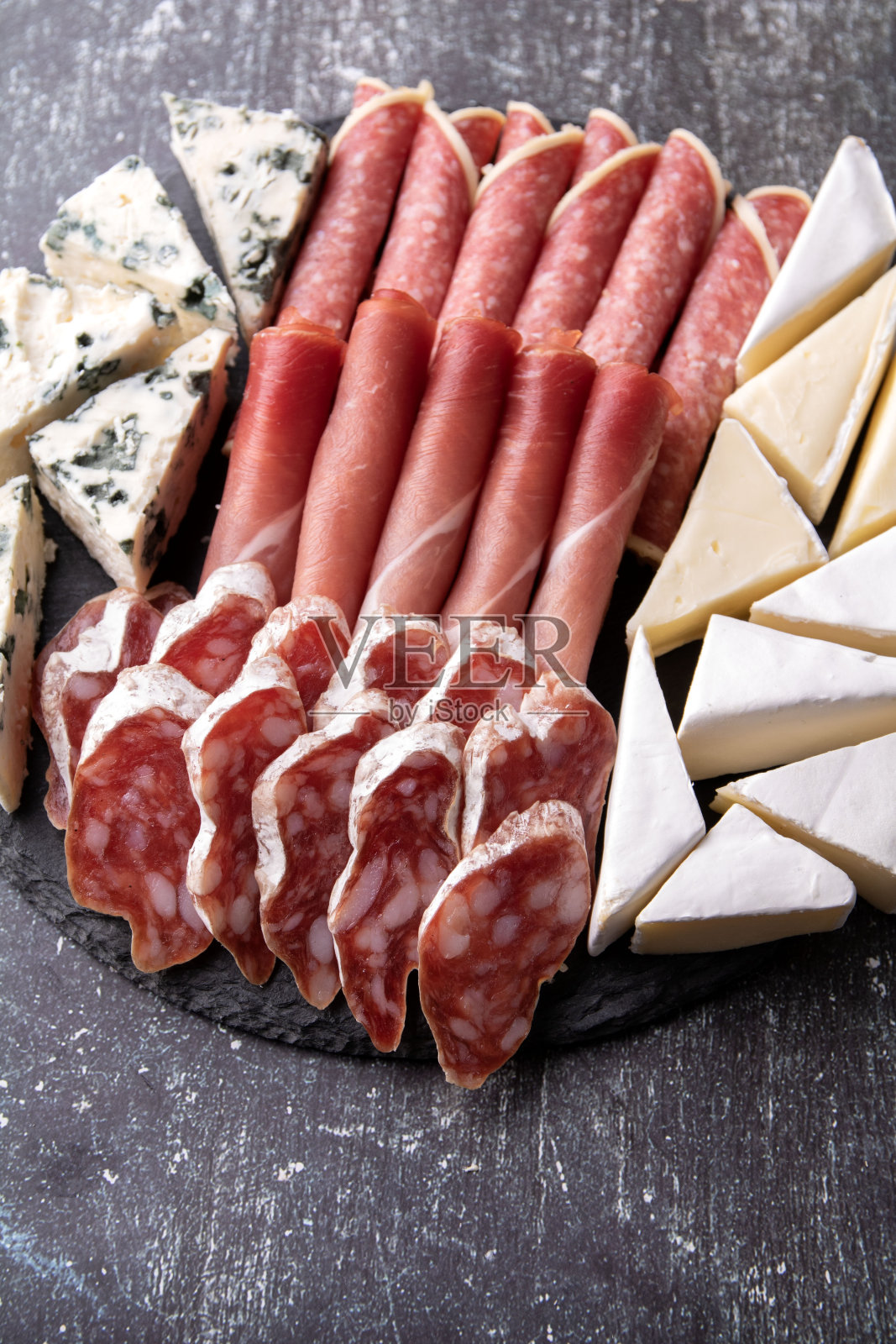 把不同种类的香肠和奶酪切片放在一个圆盘子里照片摄影图片